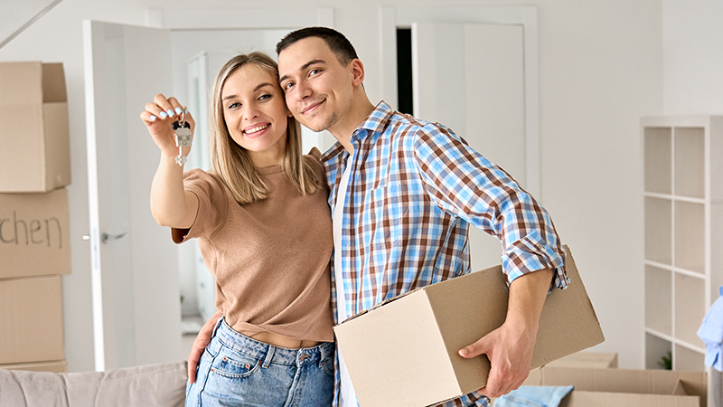 Una pareja de jóvenes está haciendo mudanza y enseña las llaves de la casa